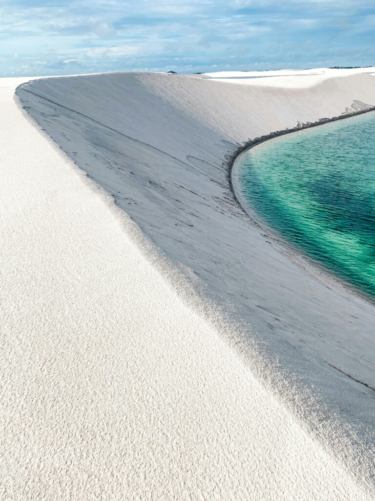 Serene beach scene showcasing white sand dunes and turquoise water under a clear sky.