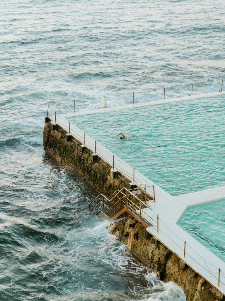 A beautiful scene of Bondi Icebergs pool with waves crashing against the rocks at Bondi Beach.